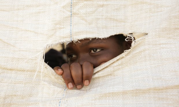A Zimbabwean secondary school student peeps through a hole in a sack that forms the wall of a makeshift classroom. Photograph: Aaron Ufumeli/EPA